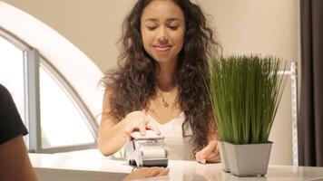 Smiling woman at a store checkout counter preparing for card payment. video