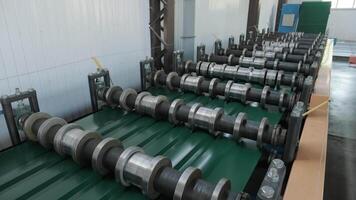 Roller conveyor line processing green painted metal sheet through compression rollers. video