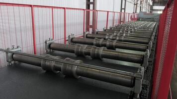 Long steel press machine guiding sheets through the rolling system inside a fenced zone. video