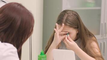 Optician supervising contact lens application for young patient. video