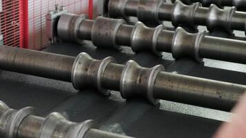 Rotating steel rollers shaping sheet metal inside a red-framed processing station. video