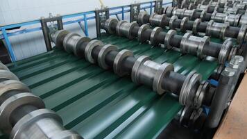 Green profiled metal sheet being processed through precision rollers in a metal fabrication line. video