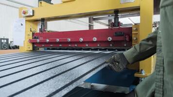 Automated cutting machine in action, slicing through textured steel sheet for roofing use. video