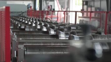Parallel rows of shaping rollers guiding sheets through a tile profile forming system. video