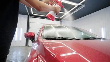 Man applying liquid car shampoo on windshield with detailing bottle. video