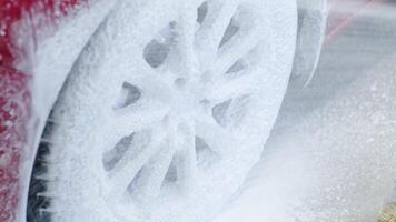 Close-up of snowy foam covering car wheel and tire before rinsing. video