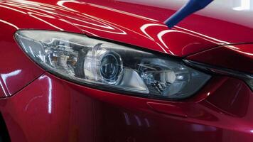 Close-up of polished headlight with reflection on shiny red paint. video