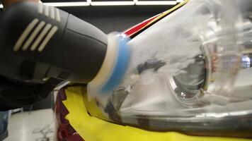 Headlight lens being polished with orbital tool during restoration work. video