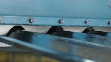 Blue metal conveyor moving shaped sheet through processing unit. video