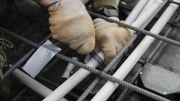 Worker securing electrical conduit with cable tie in rebar grid video