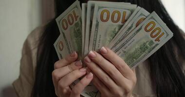 Close up of woman holding multiple hundred dollar bills in her hands Candid display reflects sense of pride and financial accomplishment in cozy indoor setting video
