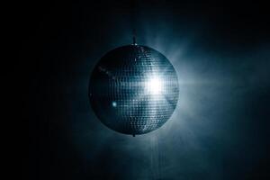 Close-up of a spinning disco ball reflecting dynamic rays of light against a black background. Perfect for creating a vibrant and energetic atmosphere at parties and events photo