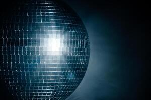 Close-up disco ball reflecting dynamic rays of light against a black background. Perfect for creating a vibrant and energetic atmosphere at parties and events photo