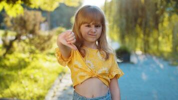 Upset child girl showing thumbs down sign, disapproval, dissatisfied bad work, mistake in city park video