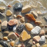 Wet Pebbles Scattered Along a Serene Beach Shore Under Gentle Waves and Soft Sunlight photo