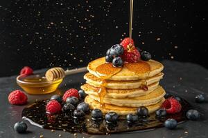 pancakes, honey and berries floating on black background, HDR image photo