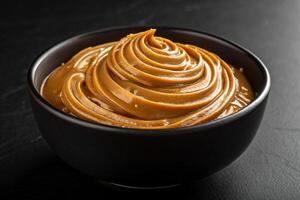 Close-up of a bowl of dulce de leche forming waves on top on black background, HDR image -generated by ai photo