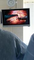 Two surgeons in lab coats and masks perform endoscopic surgery using modern equipment while looking at a monitor. Laparoscopic surgery. video