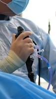 A doctor in a dressing gown, mask and rubber gloves performs a stone crushing operation in the operating room. Endoscopic surgery on the monitor. video