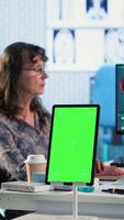 Vertical Senior medic consulting ill woman in cabinet with isolated mockup screen, checking the hospital records to do another x ray scan interpretation. Old patient discuss with her physician. Camera B. video