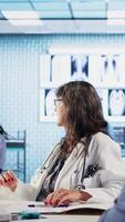 Vertical Old sick person discussing about diagnostic results and recovery plan with physician during check up, using advanced tech to get correct lab results. Patient care on health insurance. Camera A. video