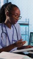 Vertical Female nurse and patients reviewing diagnostic results in medical office, using advanced healthcare technology to evaluate x ray imaging results and MRI scans. Checkup on insurance. Camera B. video