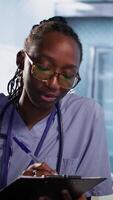 Vertical African american nurse evaluating lab test results and creating a recovery plan with elderly couple, professional patient interaction at the facility. Examination results and analysis. Camera A. video