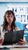Vertical Senior medic gives man patient the bad news of a disease diagnostics, medical consultation with x ray imaging visible on the screen. Healthcare problems and professional research. Camera A. video