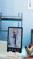 Vertical African american nurse making a videocall with doctor to chat with patients, doing a remote check up and telemedicine concept. Skilled medical assistant asks opinion of a specialist. Camera B. video