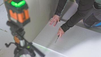 Construction worker installing floor insulation panels with laser level video