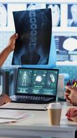 Vertical Nurse and patients reviewing diagnostic results in medical cabinet, using advanced healthcare technology to evaluate x ray imaging results and MRI scans. Patient care on insurance. Camera B. video
