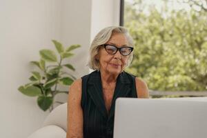 An Elegant Senior Woman Intently Working on Her Laptop in the Comfort of Her Home photo