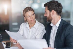 Two business people in modern office explaining statistics data to each other photo