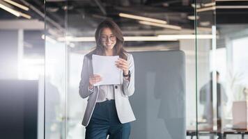 Young smiling businesswoman looking at the documents standing at office photo
