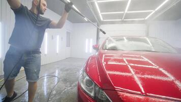 Wide view of red car being cleaned with foam jet. video