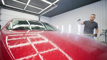 Soapy foam spreads across car surface in detailing bay. video