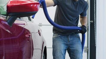 Worker using compressed air to blow dry a vehicle at auto wash. video
