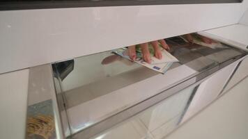 Cash being passed through a secure drawer in a payment terminal. video