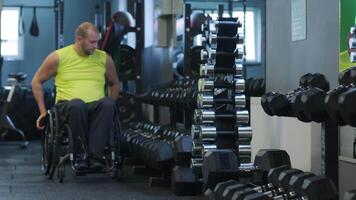 Man with a disability adjusting dumbbells in a gym environment. video