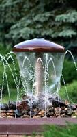 Decorative mushroom fountain with trickles on the background of greenery in the city Park. video