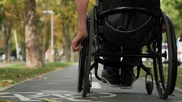 Man resting in a wheelchair on an accessible park pathway with brick paving. video