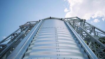 Metal silos on the field. Large containers for storing and processing grains. Silver grain elevators in farmland. Storage tank view from above. Silo with grain. video
