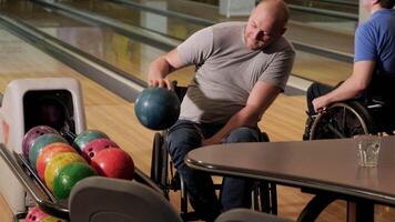 Two young with disability men in wheelchairs playing bowling in the club 40 video