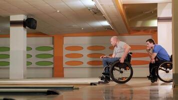 Two young with disability men in wheelchairs playing bowling in the club 4 video