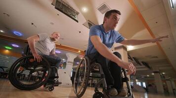 Two young with disability men in wheelchairs playing bowling in the club 38 video