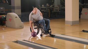 Two young with disability men in wheelchairs playing bowling in the club 24 video