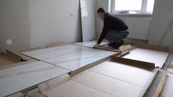 The man lays out the tiles to align the pattern. Laying large-format porcelain tiles measuring 120 by 60 on the walls. video