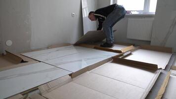 Granite tiles on the floor. The man lays out the tiles to align the pattern. Laying large-format porcelain tiles measuring 120 by 60 on the walls. video