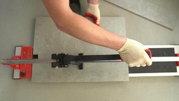 A jack-of-all-trades who uses a machine when working with tiles. A machine for cutting large ceramic tiles into smaller tiles with precise dimensions. video