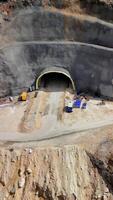 Construction workers excavating mountain tunnel in rugged terrain, using heavy machinery and precision engineering techniques for critical infrastructure project in turkey video